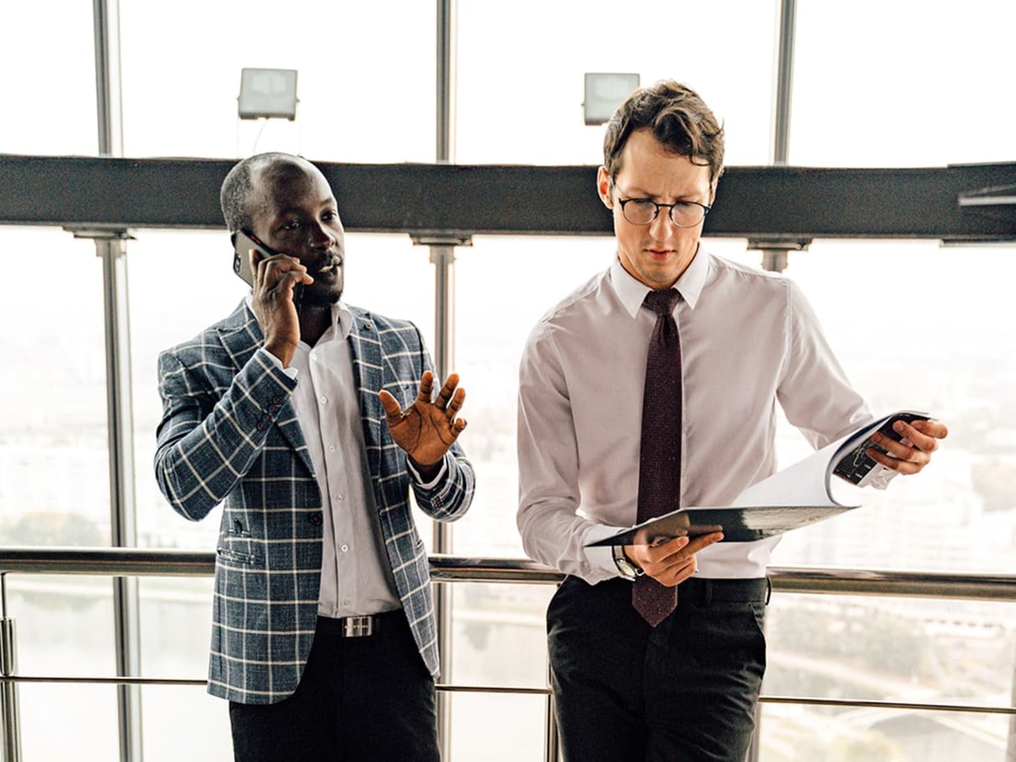 Man on the phone and another man looking at a document