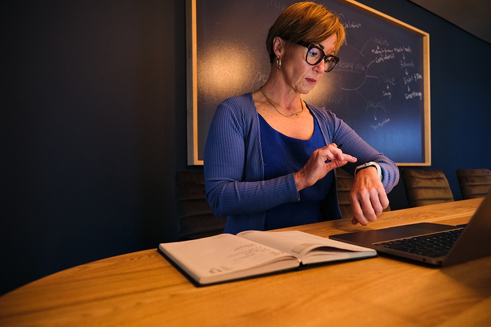 woman looking at watch sitting at desk evening