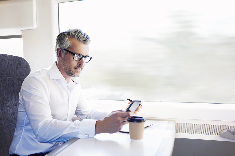 man working on train, checking email on phone 