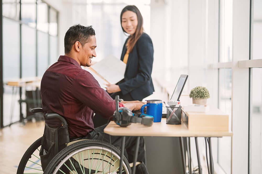 Man in wheelchair with woman working in an office