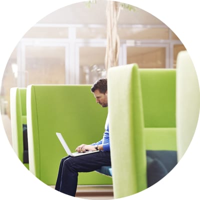 man sitting in cubby typing on laptop